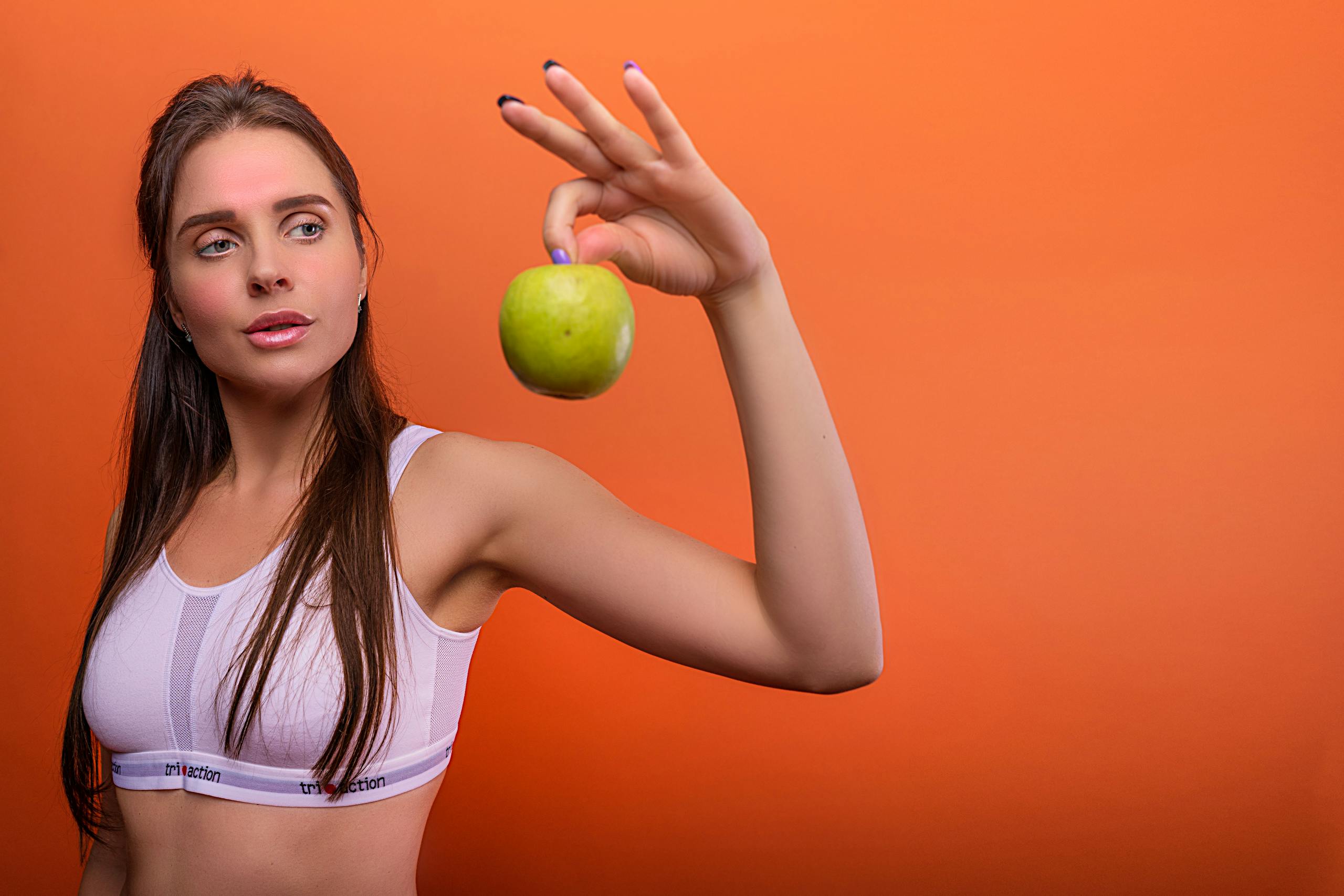 A Woman in an Activewear Holding a Green Apple